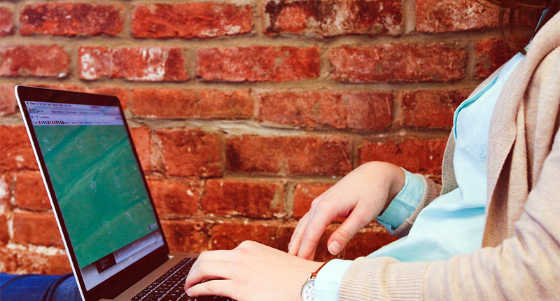 Frau mit Laptop sitzt auf Bank